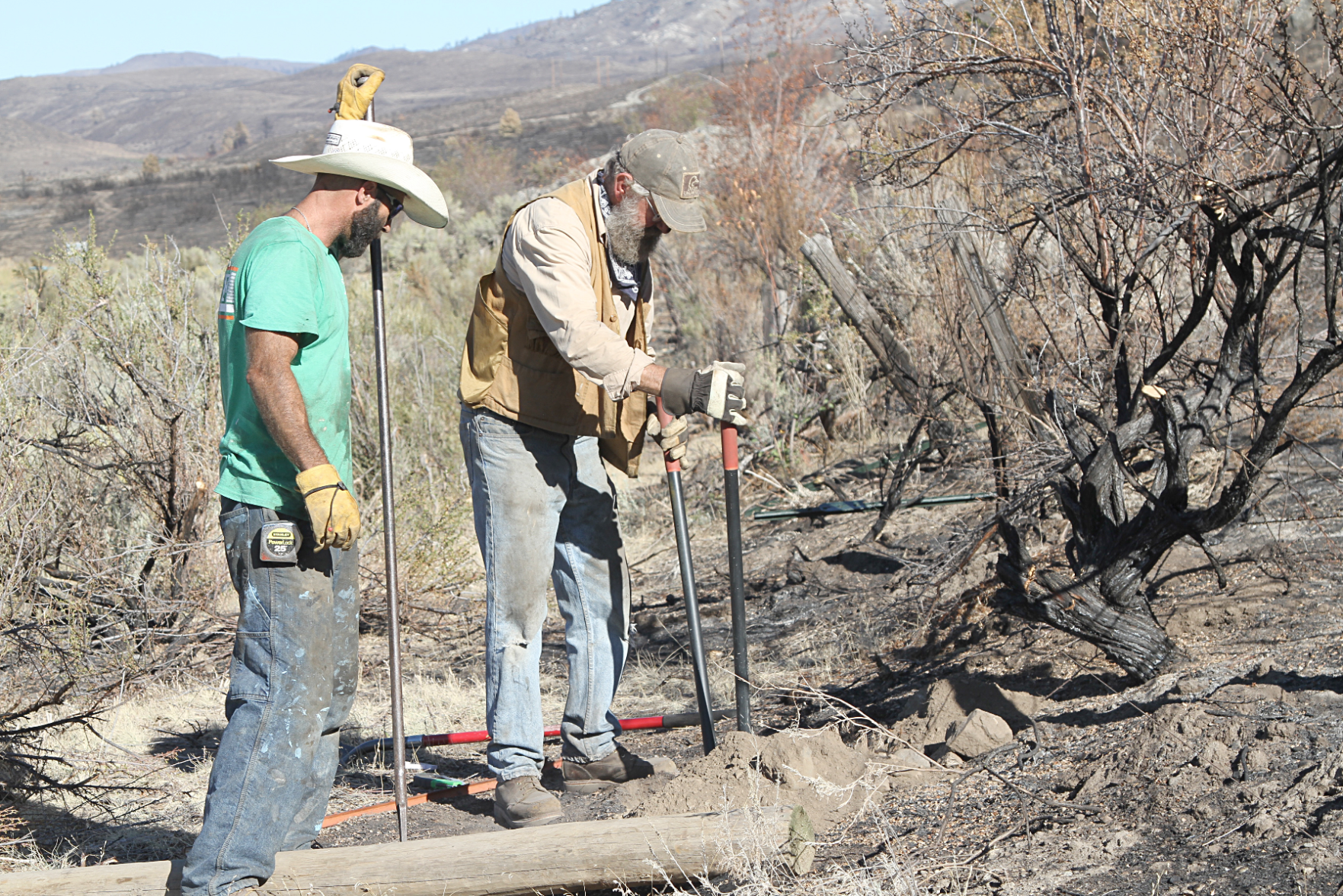 Volunteers Mark Tesch, right, and Dennis Hoots, left, rebuild fence near Highway 97, Tuesday, in an effort to help the community recover from the Cold Springs Fire that burned approximately 190,000 acres on the Colville Indian Reservation.
